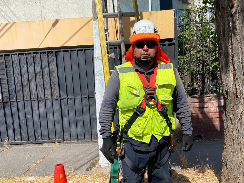 Técnico con casco, chaleco reflectante y arnés de cuerpo completo.