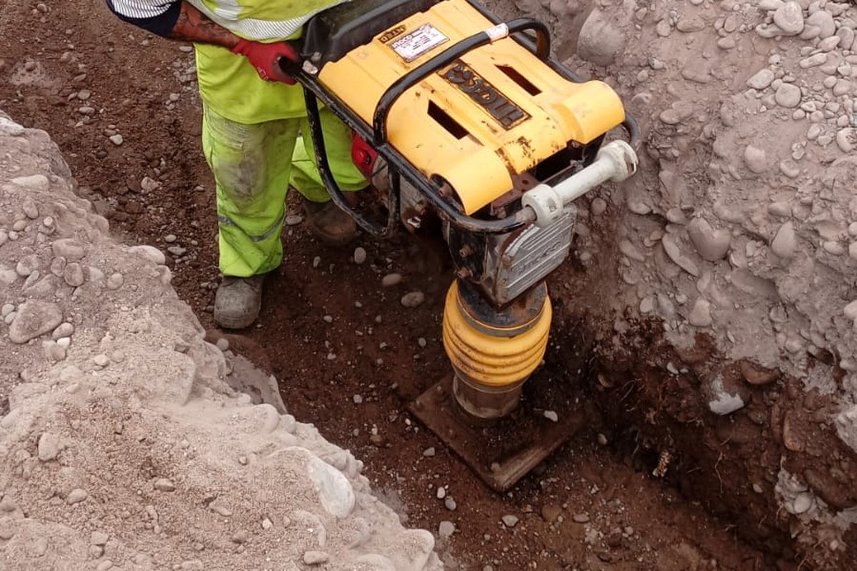 Compactación del fondo de zanja con apisonador antes de tender los ductos.